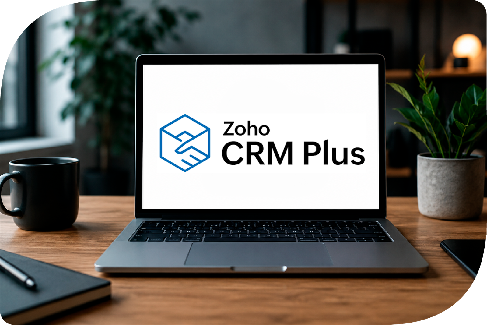 Laptop med Zoho CRM Plus logo på skærmen i moderne kontormiljø, som symboliserer samlet platform til salg, marketing og kundeservice.