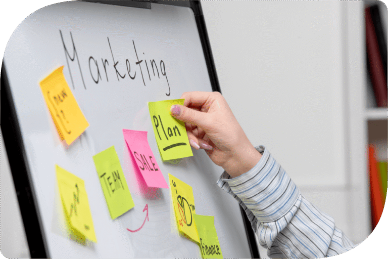 Person planlægger marketing automatisering og kampagner på whiteboard med noter og strategioversigt.